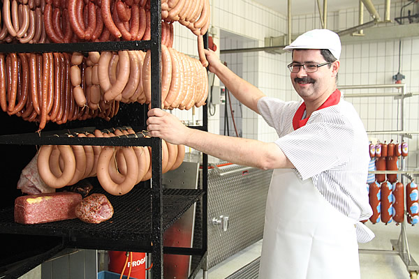 Ein Metzger mit einem Wagen voller Wurstwaren in der hauseigenen Metzgerei